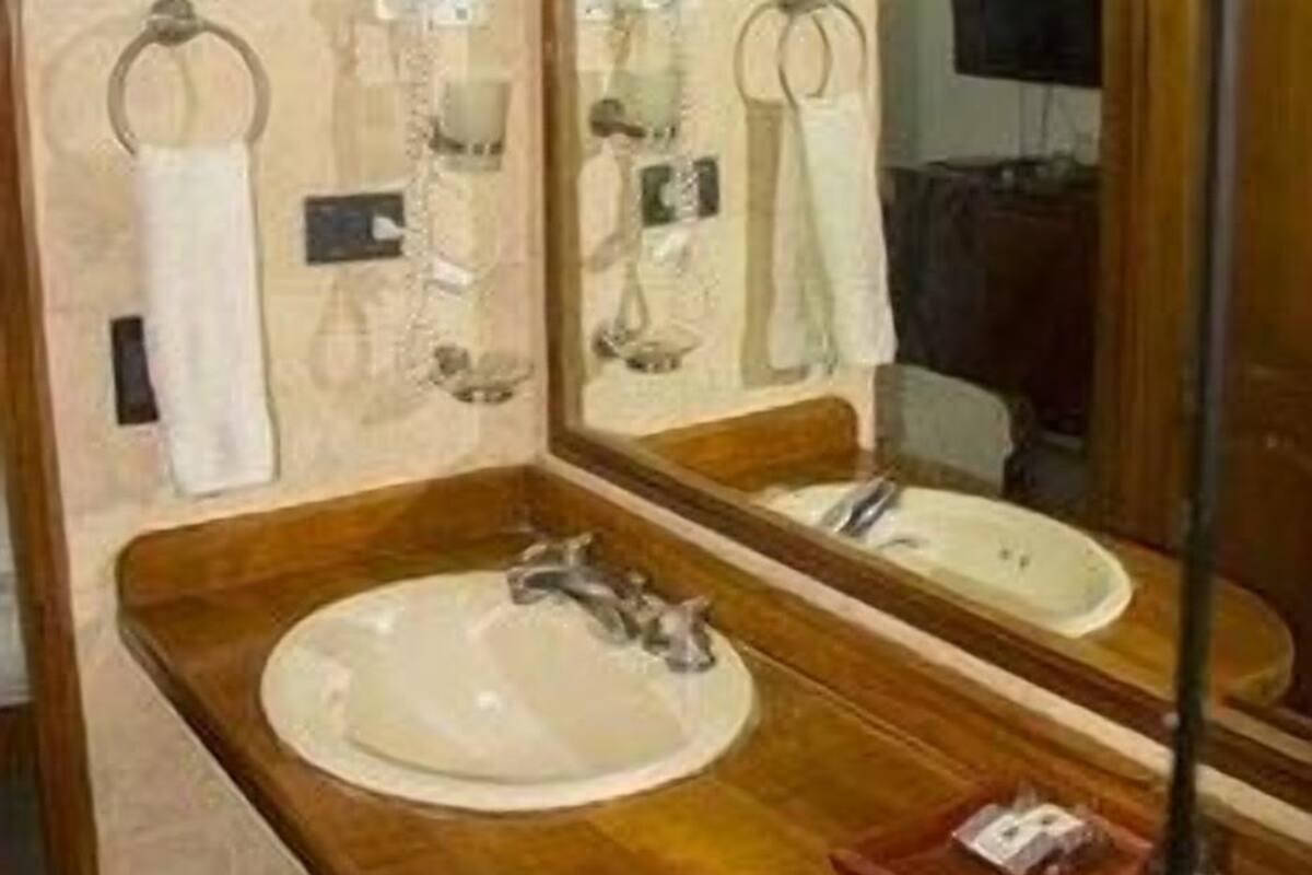 Een badkamer met een houten wastafelmeubel, een wastafel, een spiegel en een handdoekhouder.