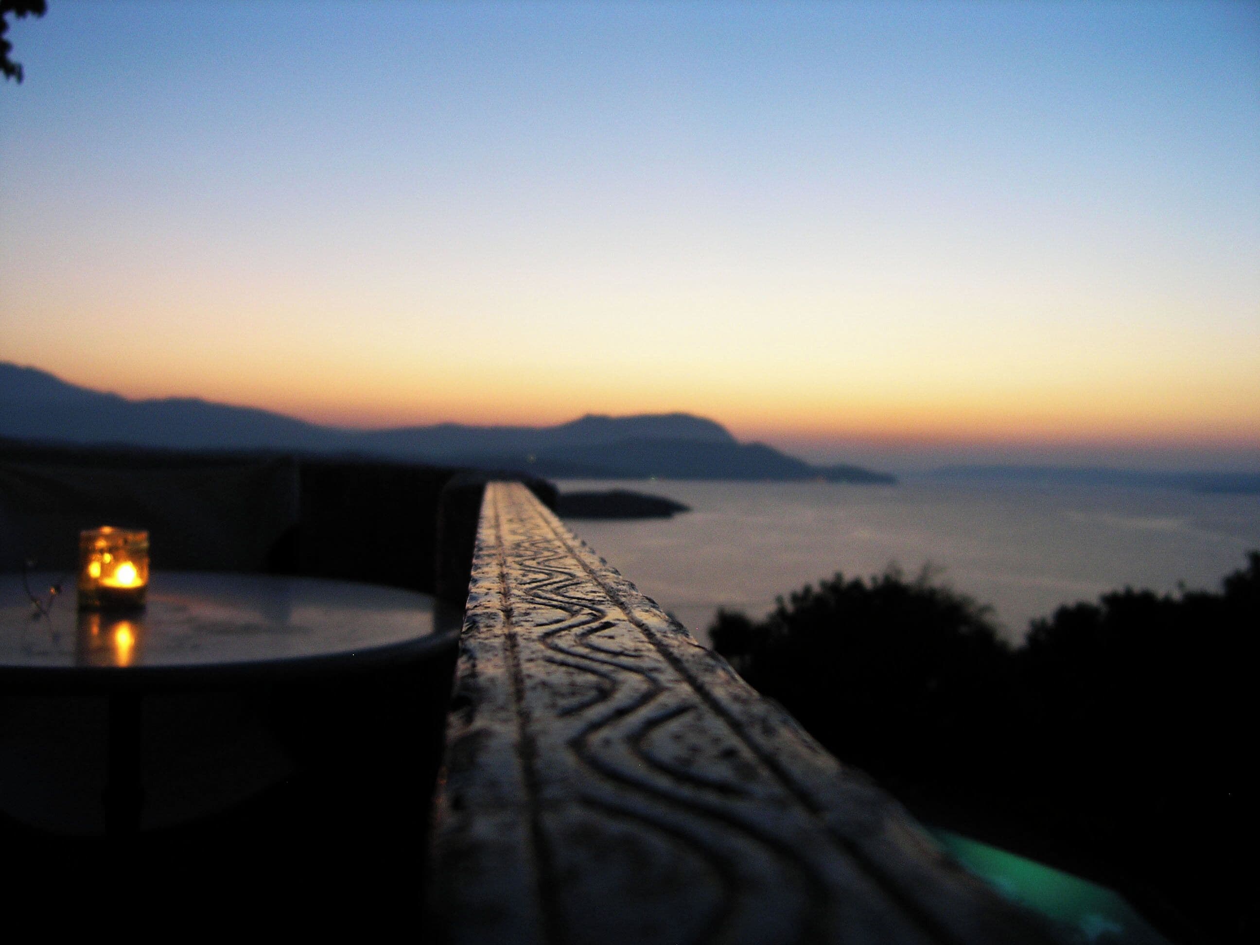 A sunset view from a balcony with a table and a candle.