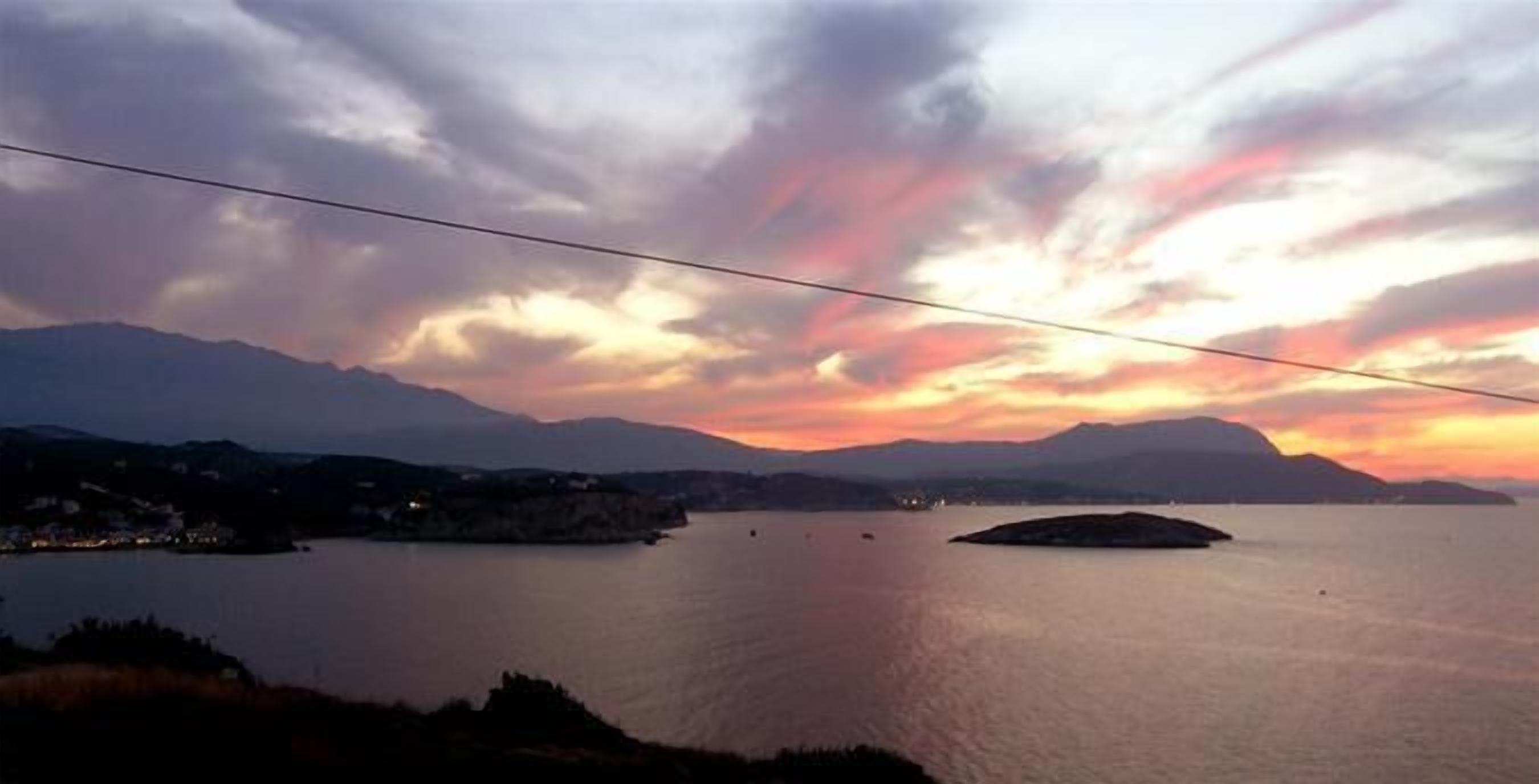 A calm lake with mountains in the background and a sunset sky.