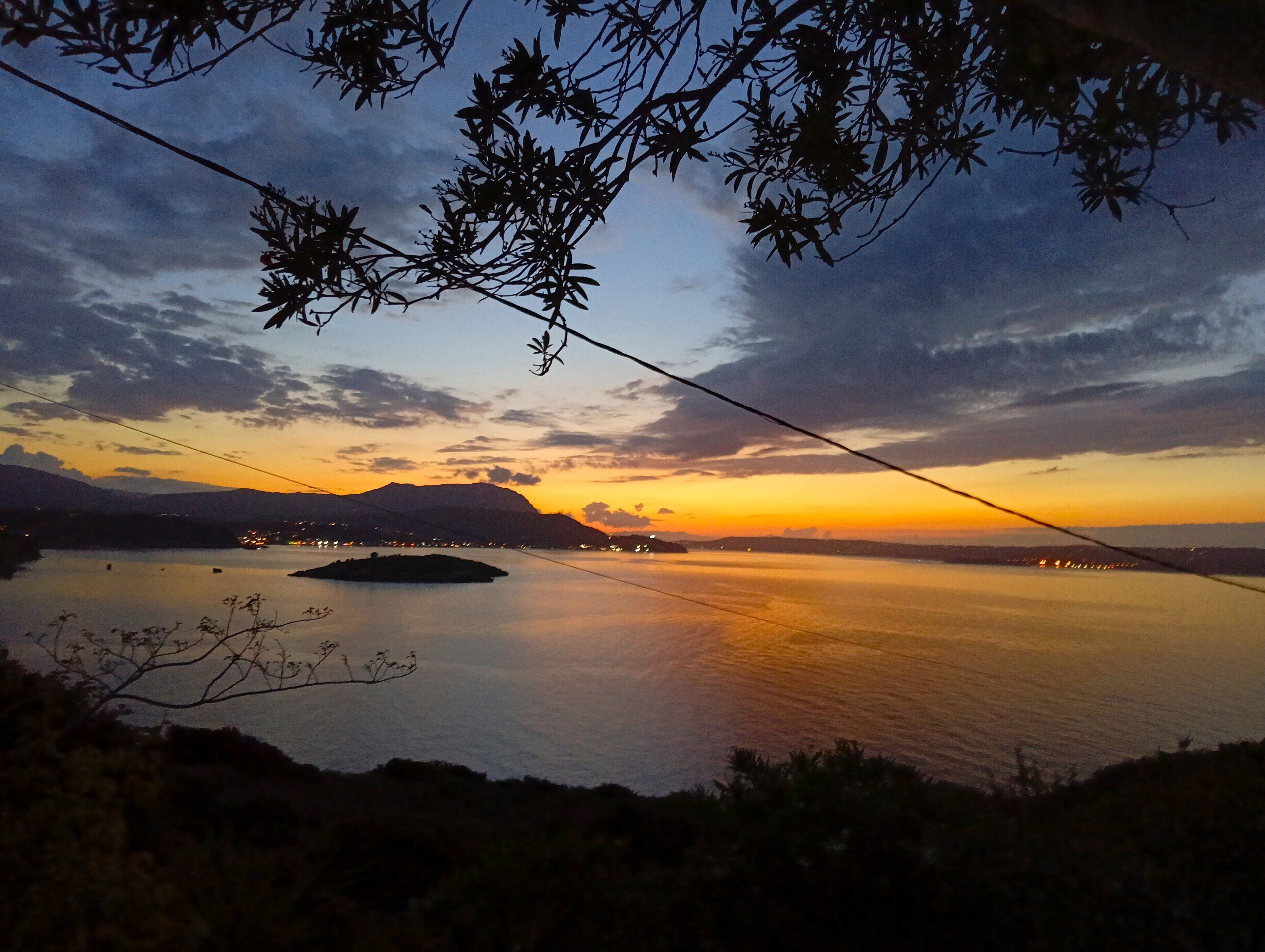 Una vista al atardecer sobre un lago tranquilo, con montañas lejanas y una pequeña isla.
