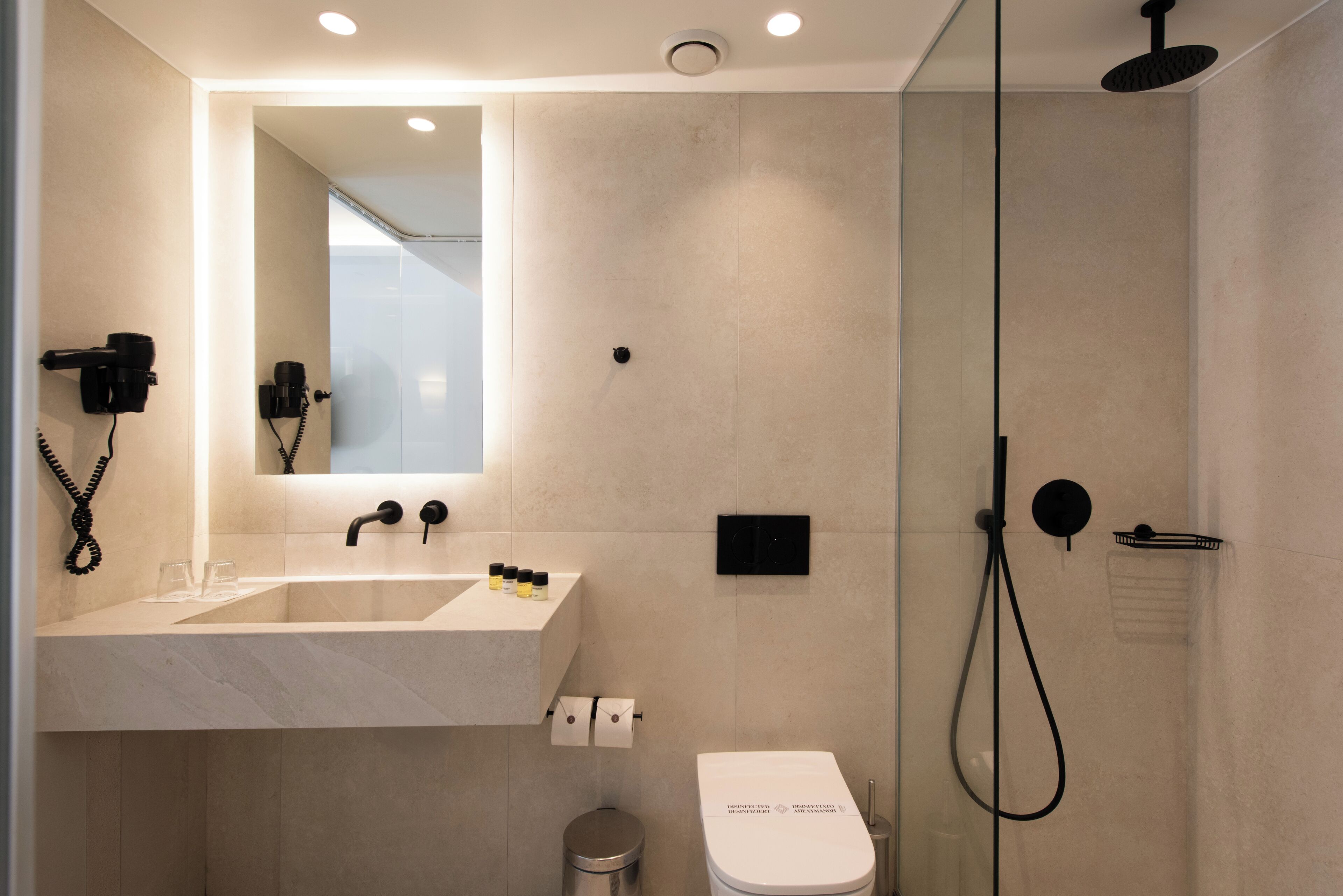 A modern bathroom with a sink, mirror, toilet, and shower.