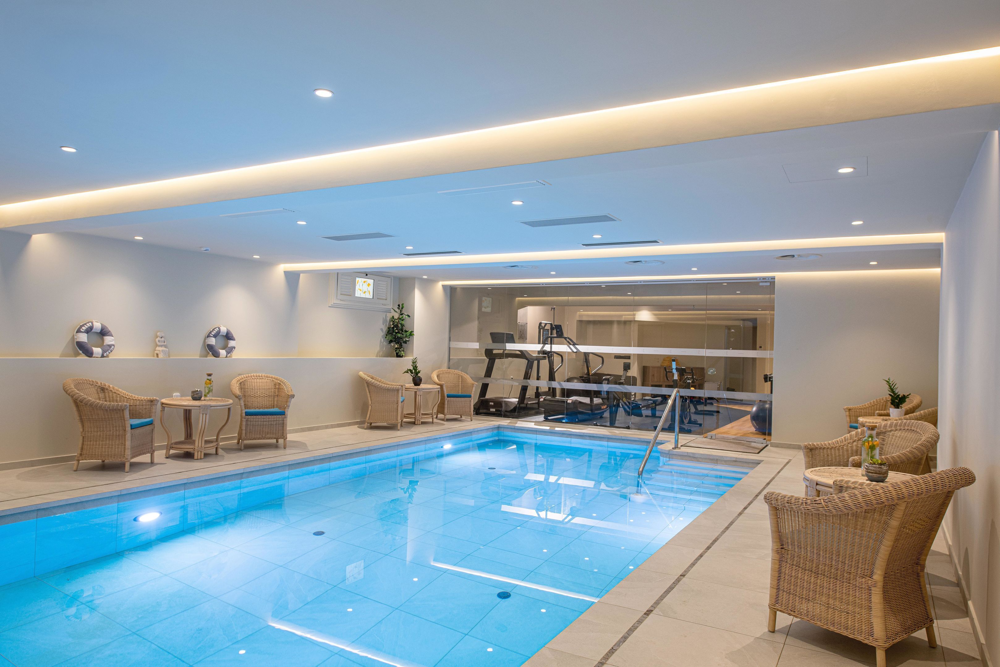 Una piscina con sillones de descanso y un espacio para gimnasia.