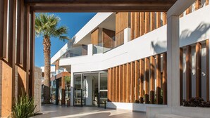 Un edificio moderno con fachada de madera, ventanas amplias y una palmera en primer plano.