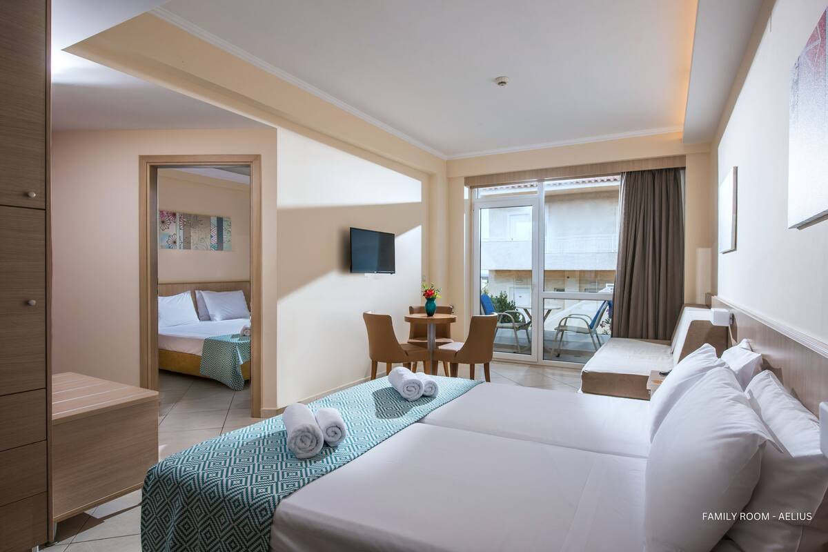 A family room with a bed, a desk, and a balcony with a table and chairs.