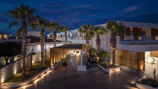 Un patio de hotel moderno con palmeras, un paseo techado y un carrito de golf.