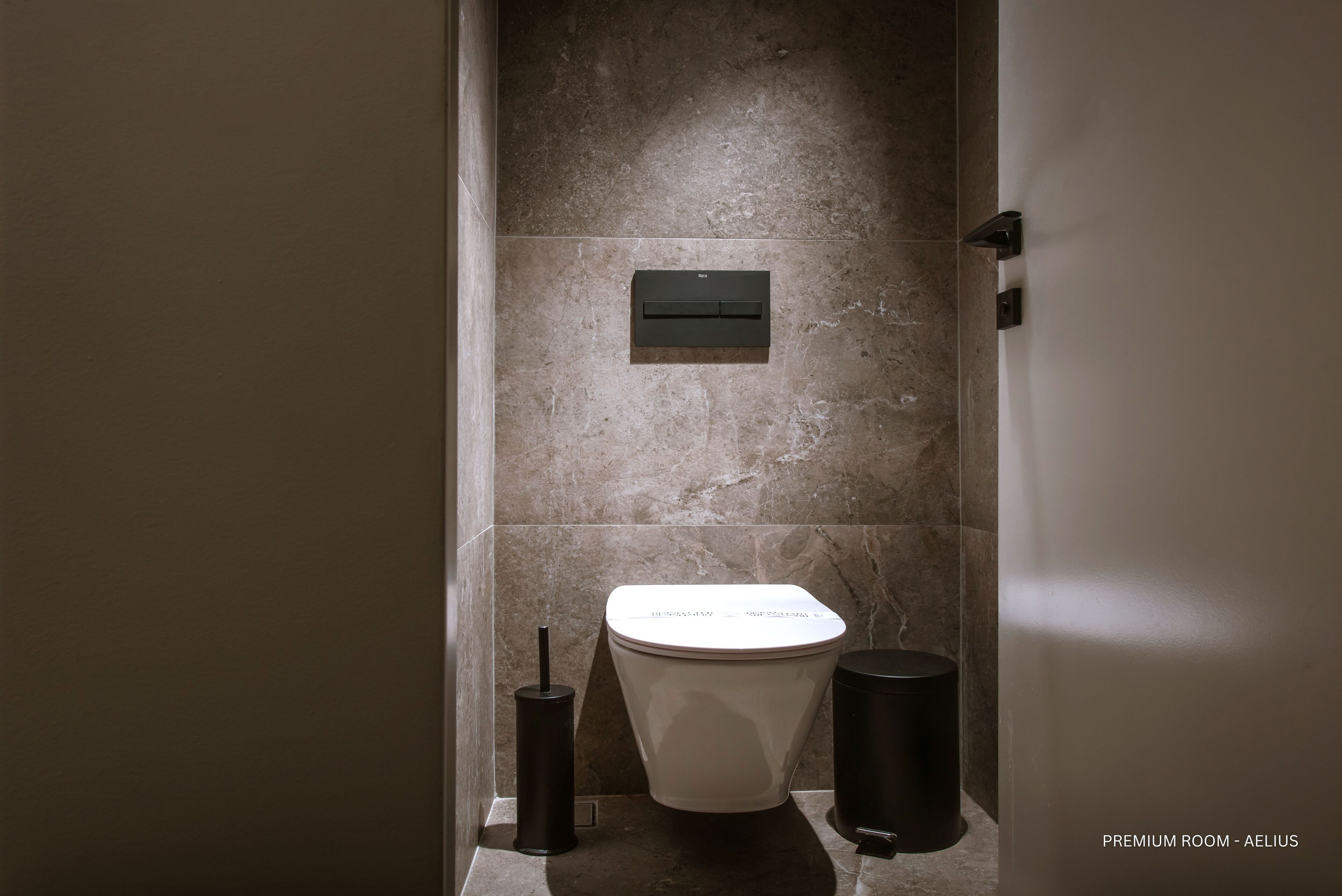 A modern bathroom with a toilet, bidet, and trash can.