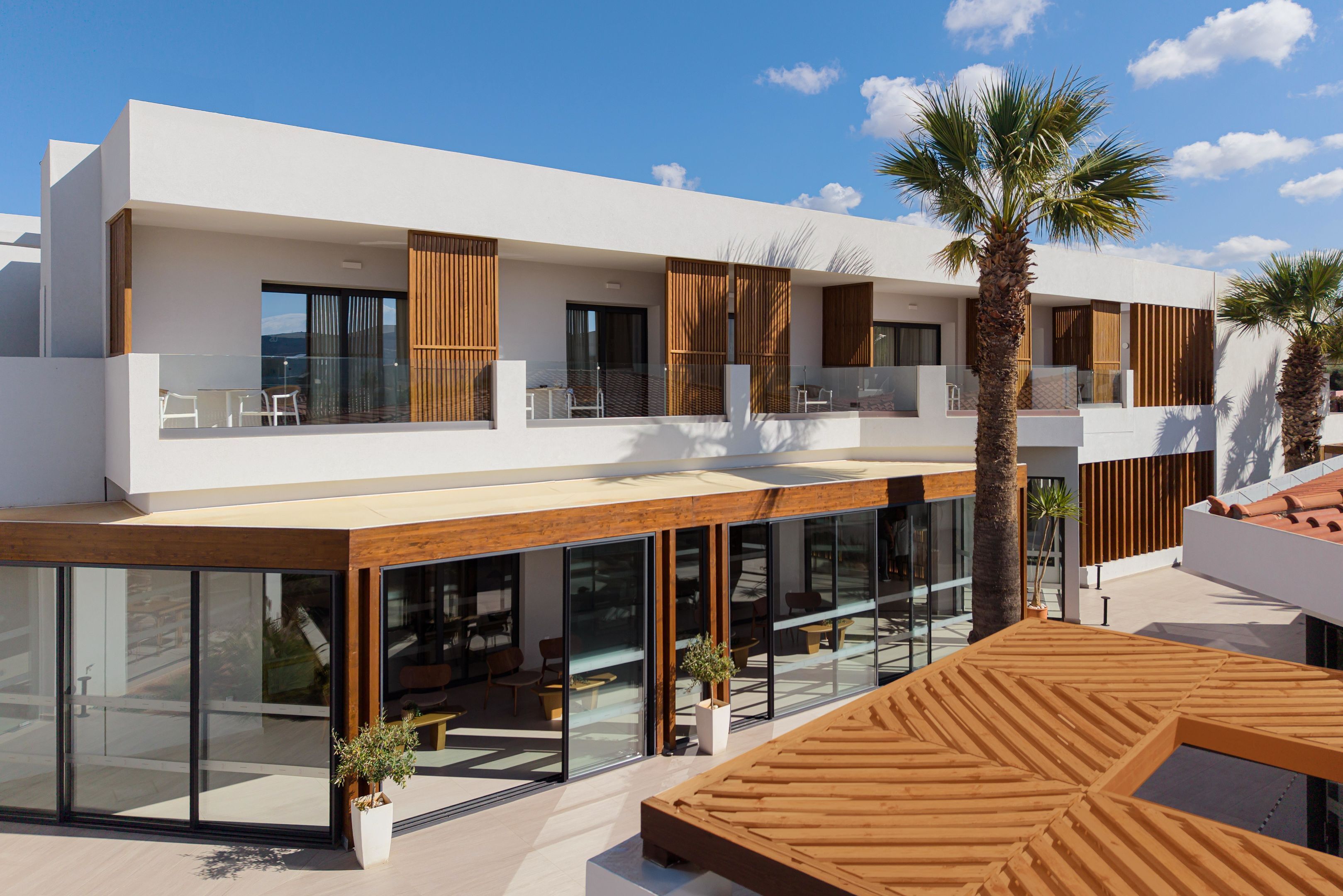 A modern two-story building with a flat roof, large glass windows, and wooden accents.