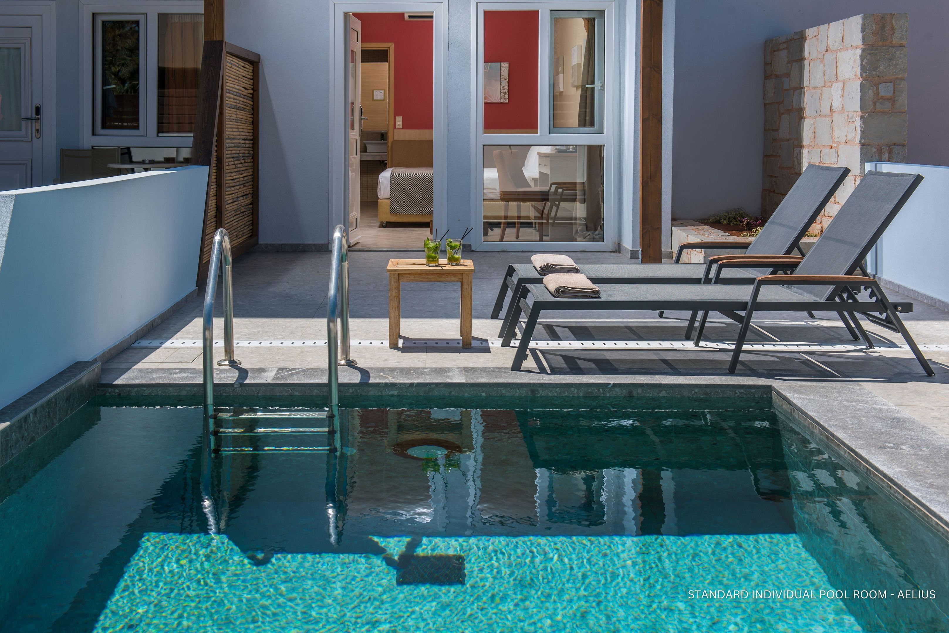 A standard individual pool room with a clear pool, lounge chairs, a small table with drinks, and a view of the interior.