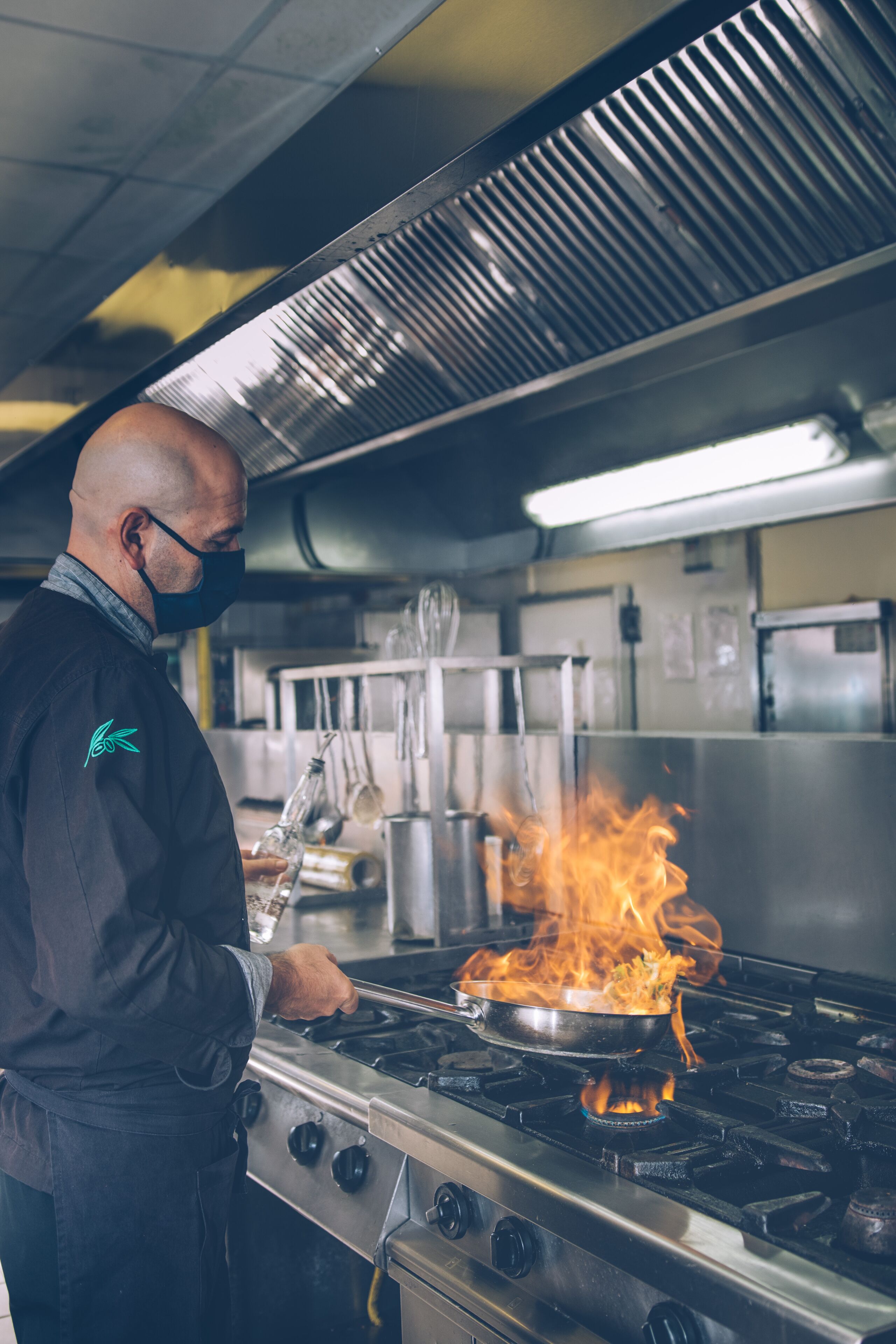 A chef cooking on a gas stove with flames.
