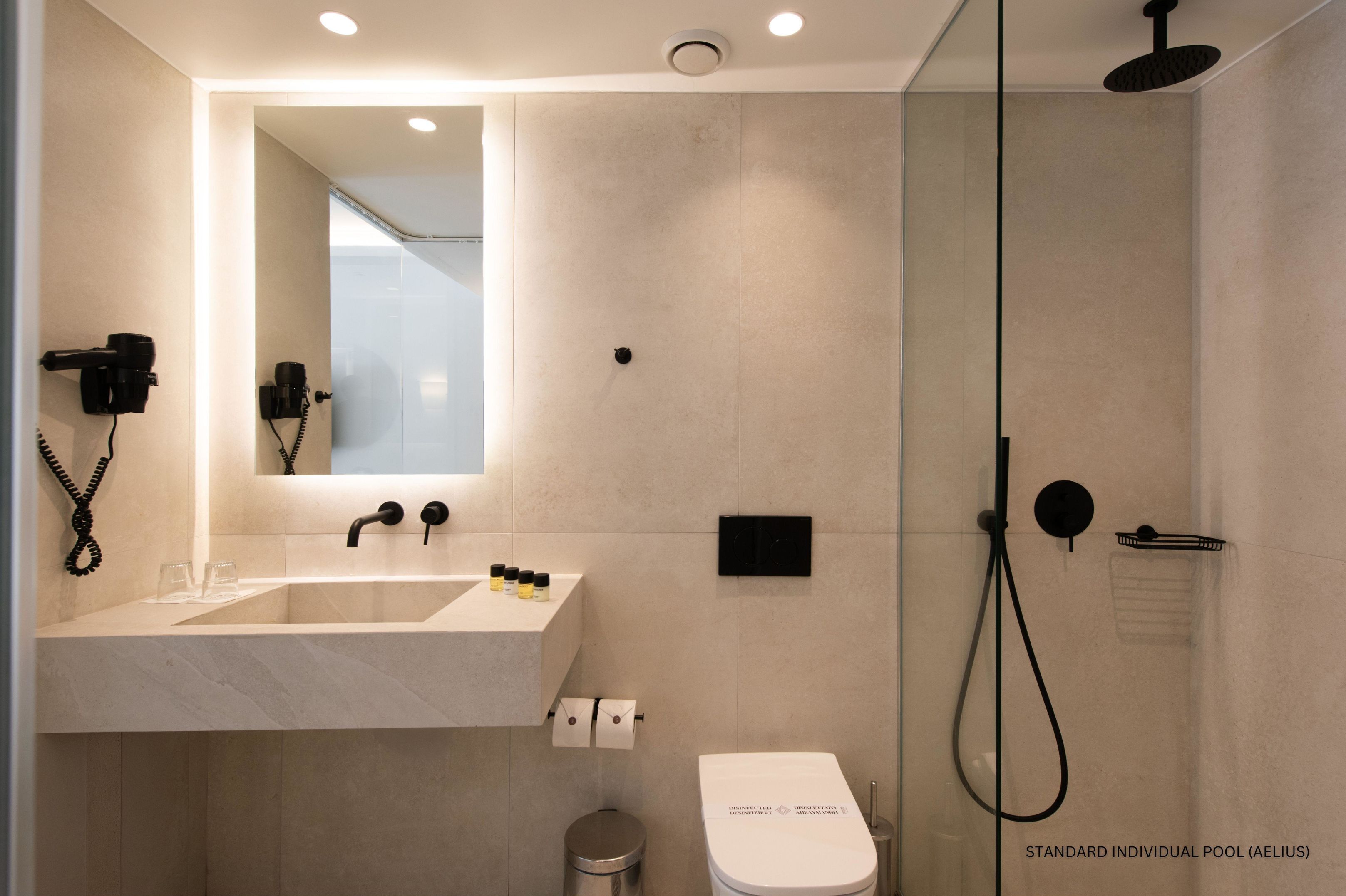A modern bathroom with a large mirror, a sink, a toilet, and a shower.
