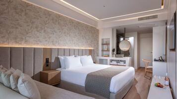 A modern executive room with a large bed, bedside tables, a desk, and a seating area.