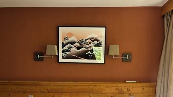 A neatly made bed with two pillows, a framed picture on the wall, and two bedside lamps.
