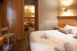 A wooden-paneled room with a bed, a chair, and a nightstand. - LOGIS HOTEL LE MONAL (Sainte-Foy-Tarentaise)
