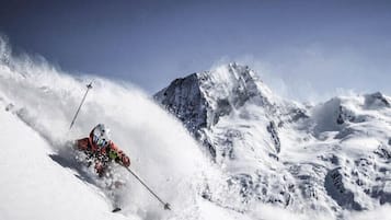 Un esquiador deslizándose por una pendiente nevada y empinada.