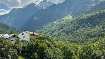 A mountain landscape with a house in the foreground and a view of the mountains in the background.