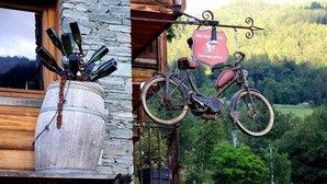 A rustic wooden building with a stone barrel, a bicycle, and a sign indicating a garage parking area.