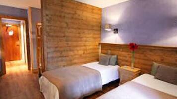 Une chambre d’hôtel avec deux lits, des murs en bois et une table de chevet avec une lampe.