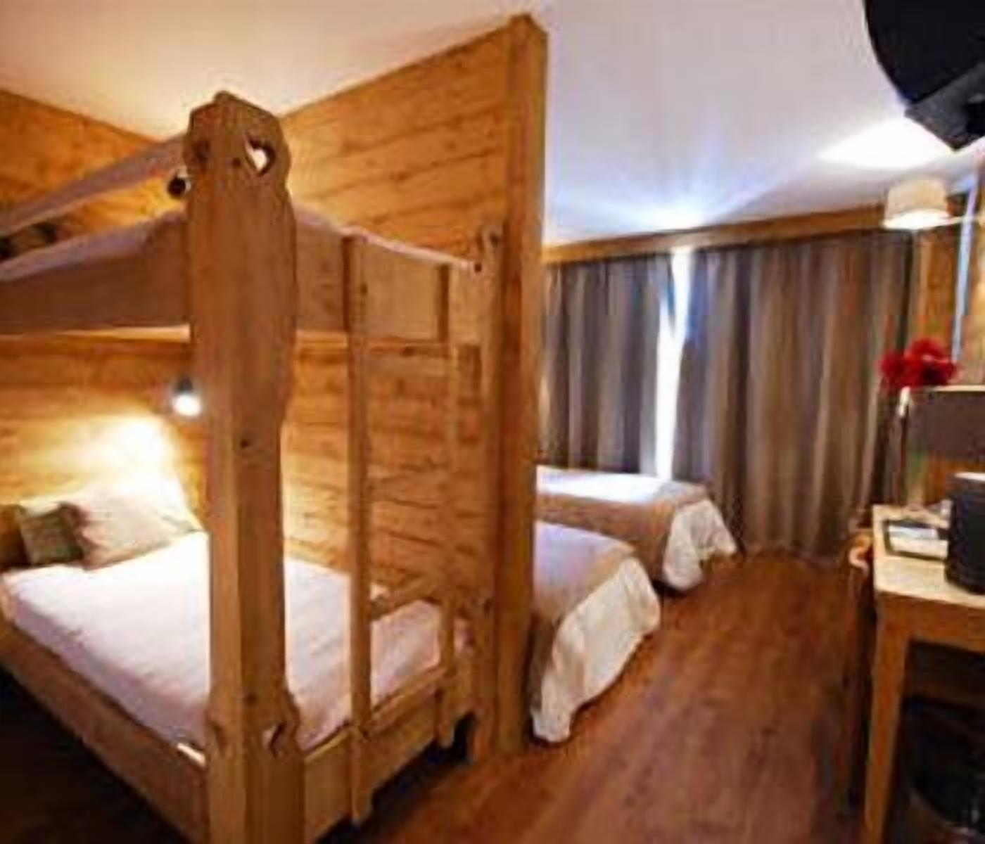 A wooden bunk bed room with a desk and chair, curtains, and a lamp.