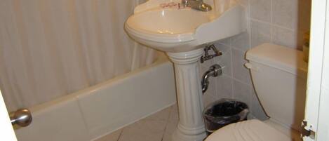 Une salle de bain avec un lavabo sur colonne, des toilettes et une baignoire.