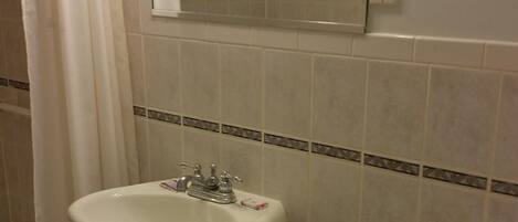 Un baño con lavamanos, inodoro y cortina de ducha.