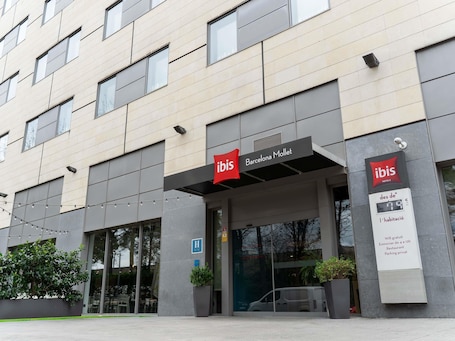 A modern hotel facade with 'ibis Barcelona Mollet' signage, a digital display, and a wheelchair accessibility symbol.. ibis Barcelona Mollet