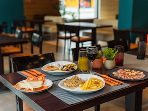 Un tavolo da pranzo con piatti di cibo, un bicchiere di succo e un bicchiere di vino rosso.