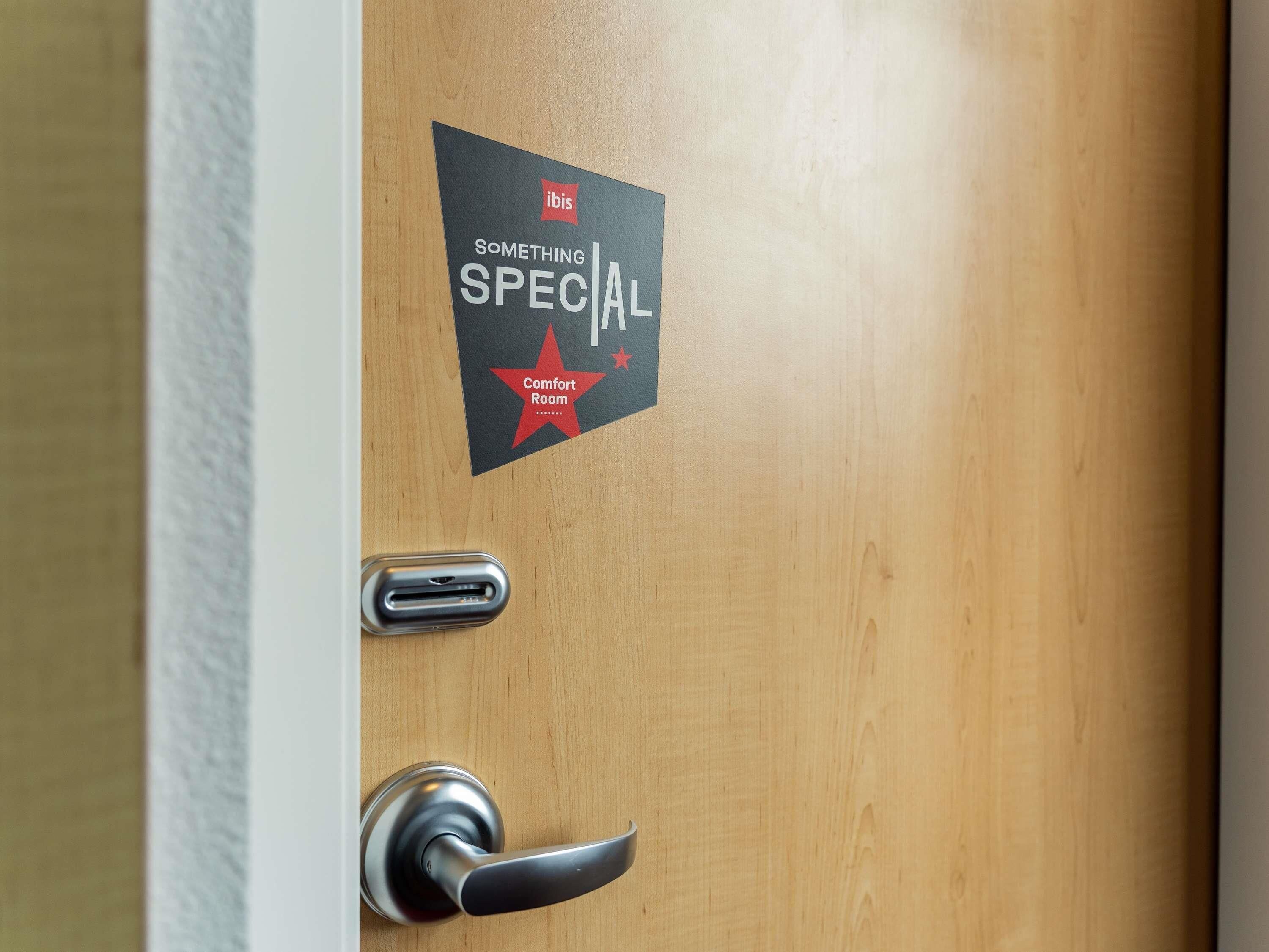 Una puerta con un cartel que dice 'ibis SOMETHING SPECIAL Habitación Confort'.