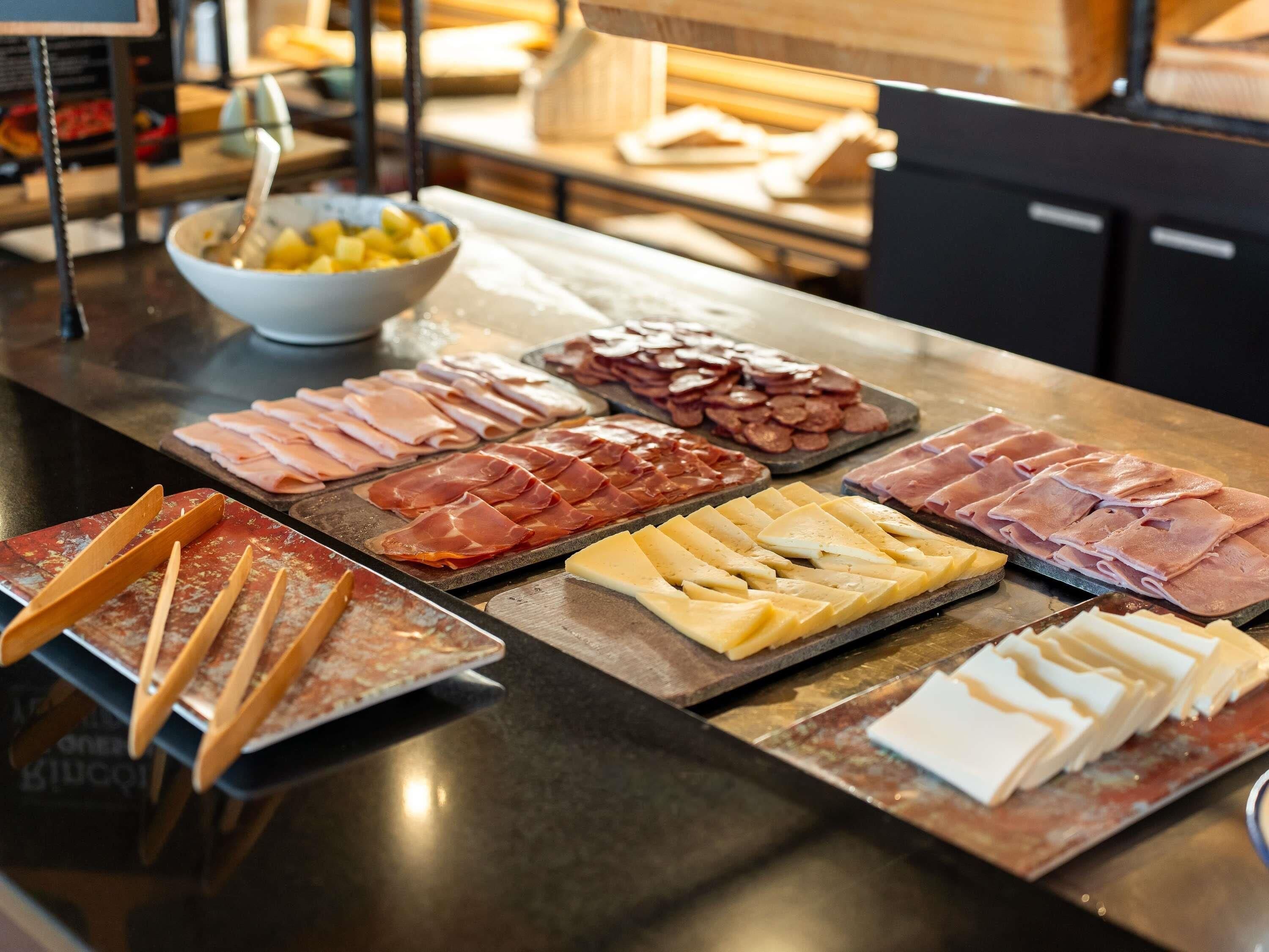 A buffet with various meats and cheeses.