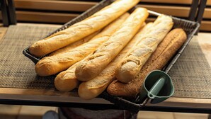 Una cesta de barras de pan sobre una mesa con un mantel tejido.