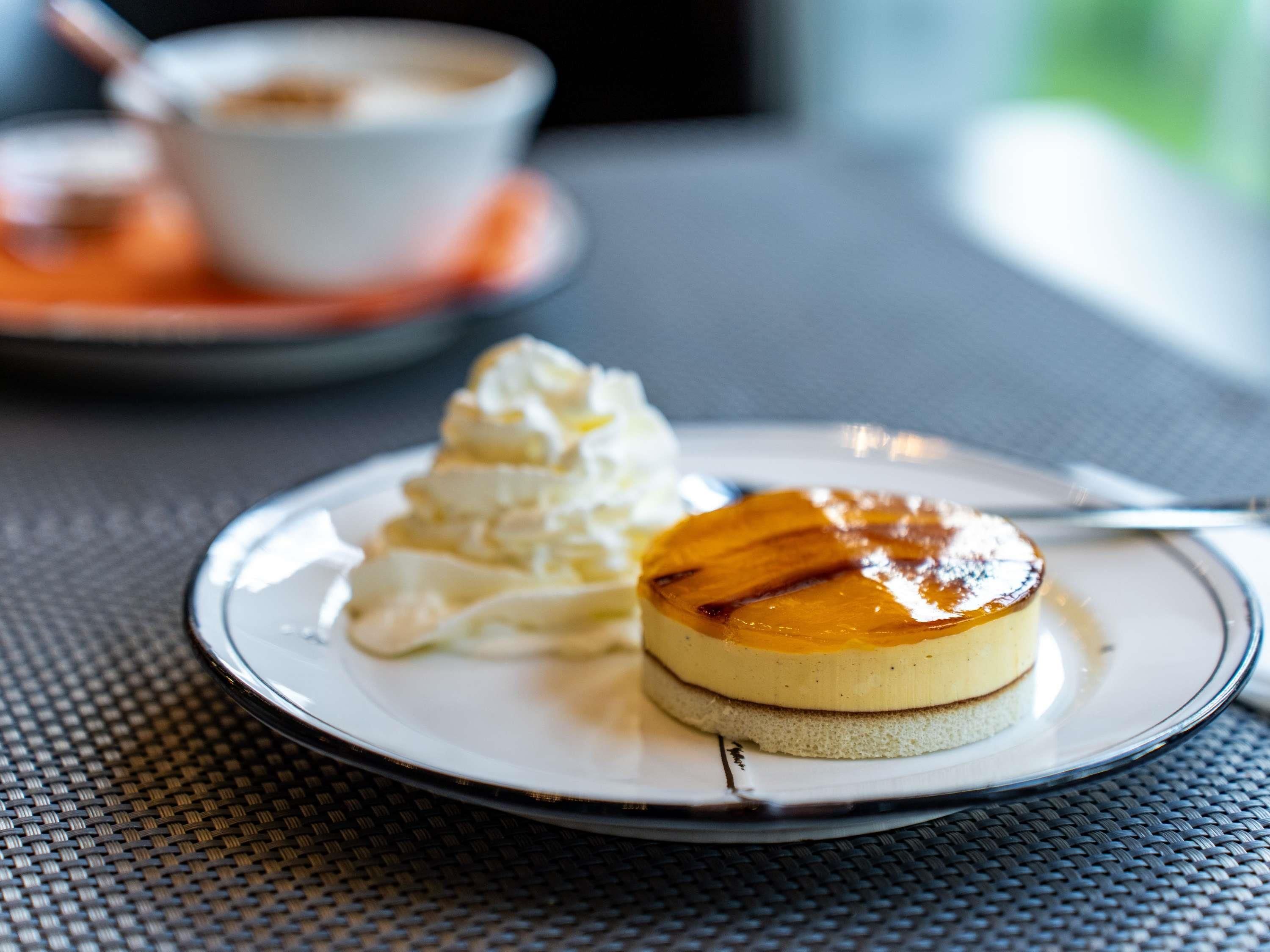 Un plato de postre con flan y crema batida sobre una mesa.