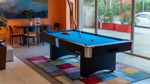 Una mesa de billar con bolas, una vara y un porta-varas.