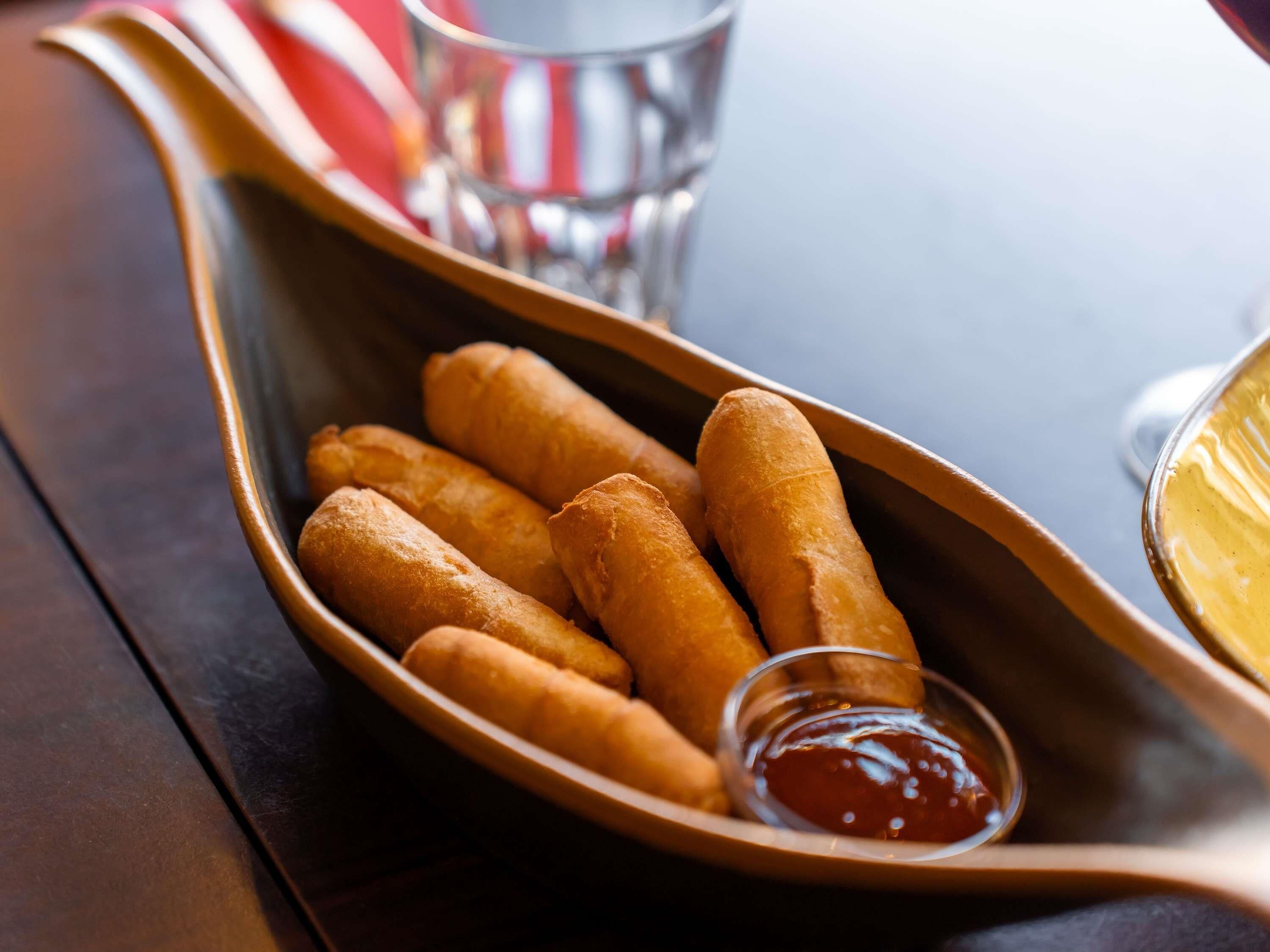 A tray of golden-brown fried items with a small bowl of red sauce.