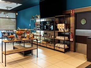 A cafe with a wooden table, shelves with jars and bowls, and a fire extinguisher. - ibis Barcelona Ripollet (Ripollet)