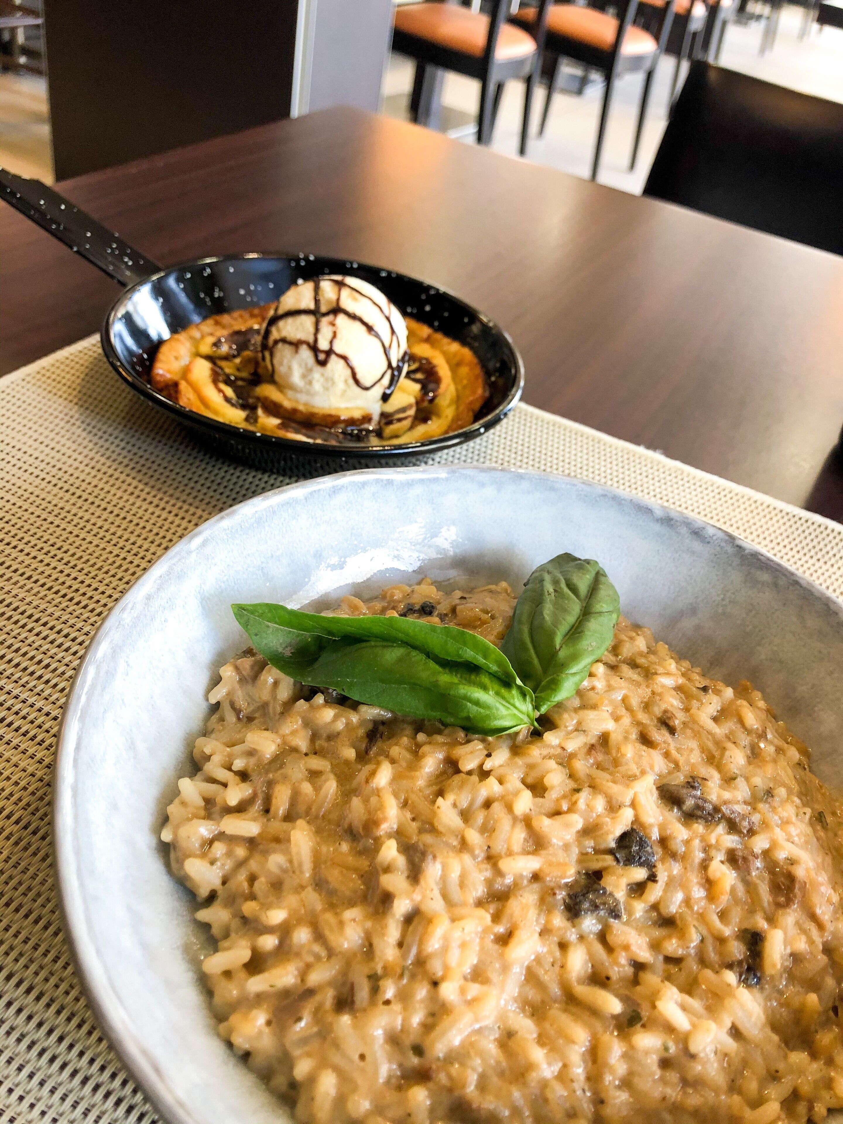 Un plato de risotto con decoración de albahaca sobre una mesa.