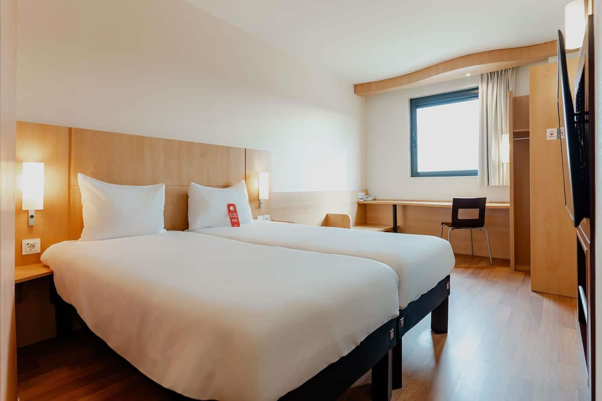 A hotel room with a large bed, bedside tables, a desk, and a chair.