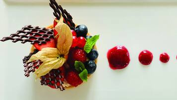 A dessert with strawberries, blueberries, and chocolate on a white plate.