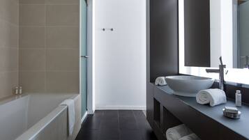 Un baño moderno con bañera, lavamanos grande y espejo.