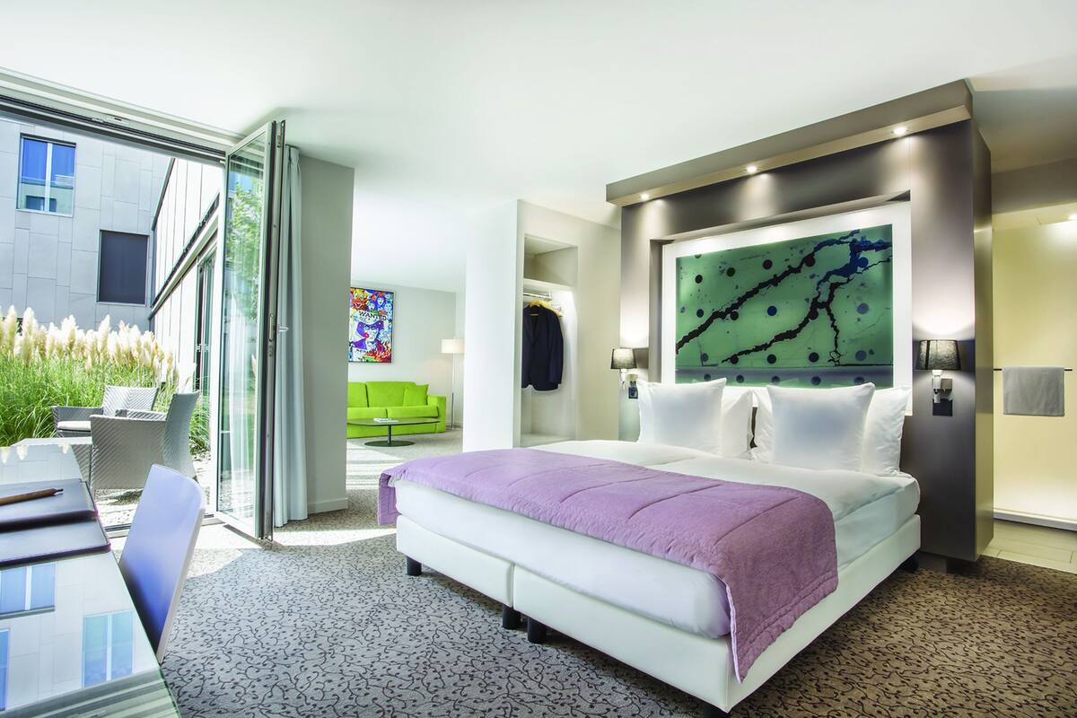 Habitación de hotel moderna con una cama grande, un escritorio y vistas al exterior.