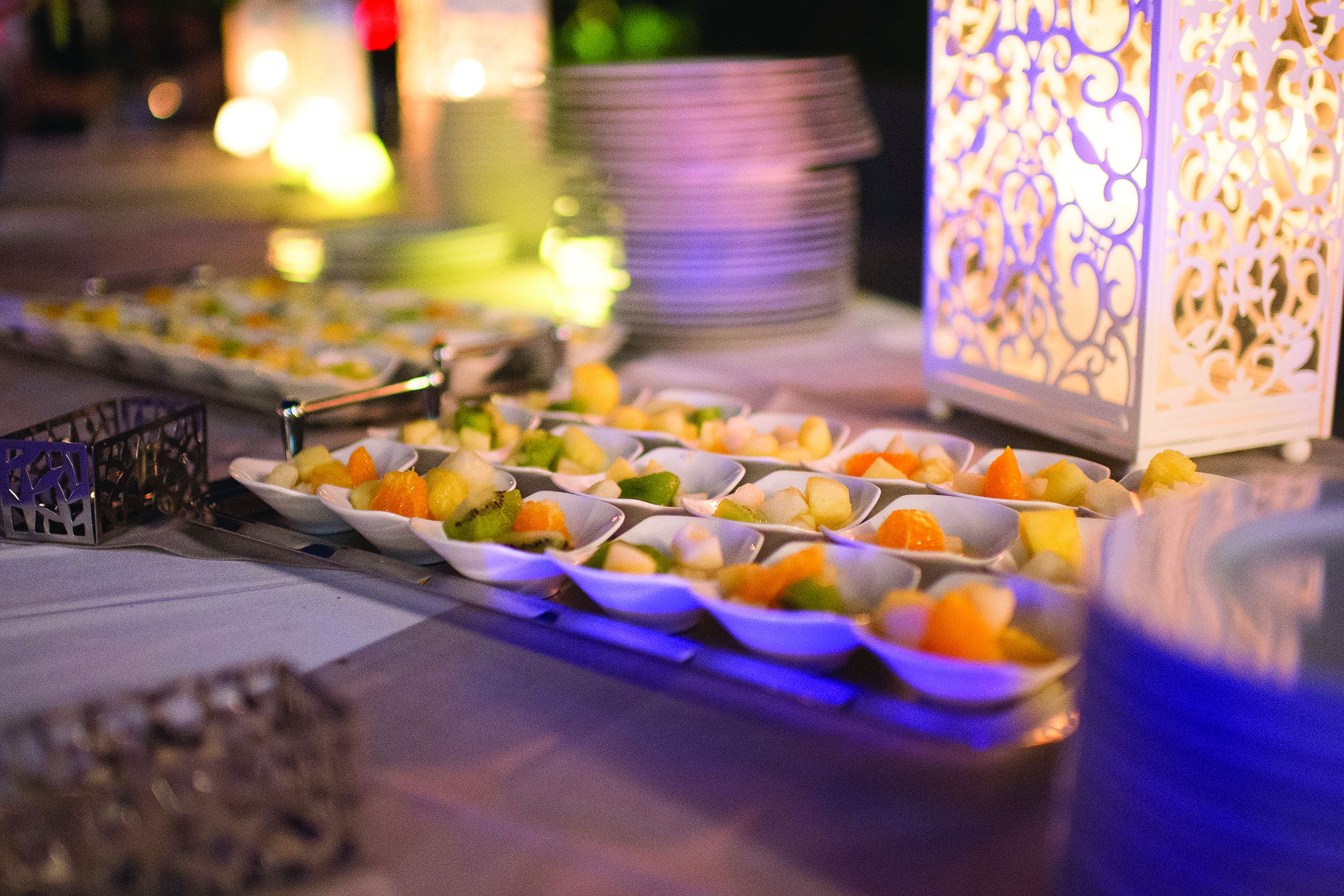 Una mesa de buffet con diversas frutas y un farol decorativo.