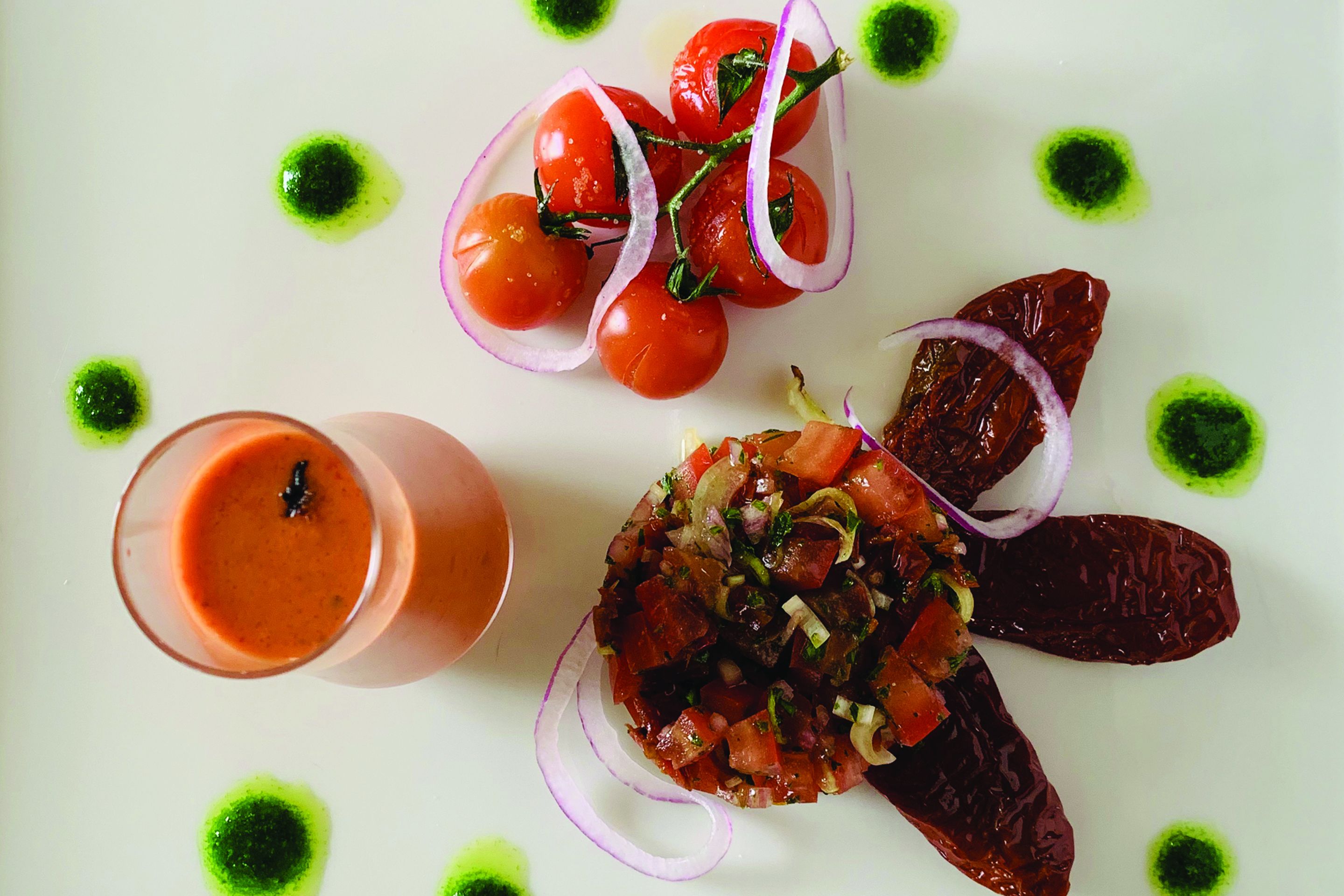 Ein Teller mit Tomatensalat, Cocktailtomaten und ein Glas Tomatensuppe.