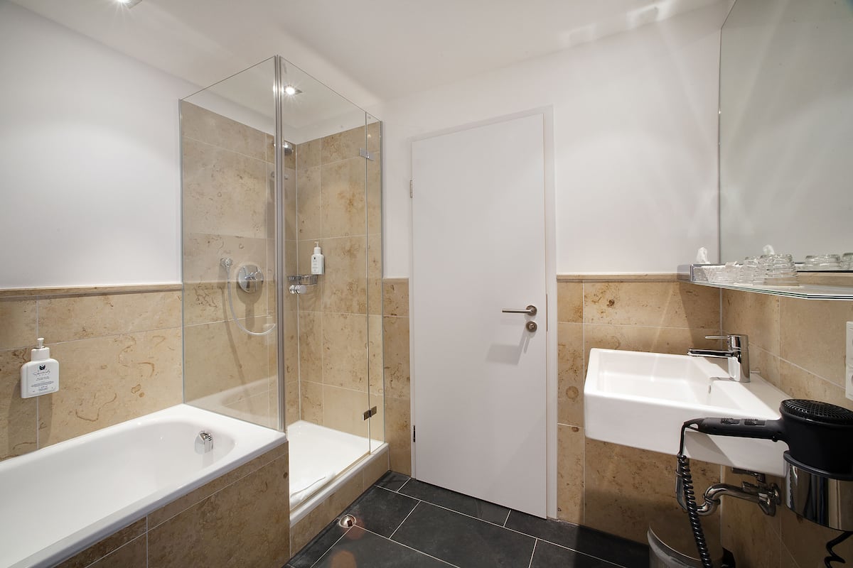 Une salle de bain moderne dotée d’une douche à parois de verre, d’une baignoire sur pieds et d’un lavabo avec un sèche-cheveux.