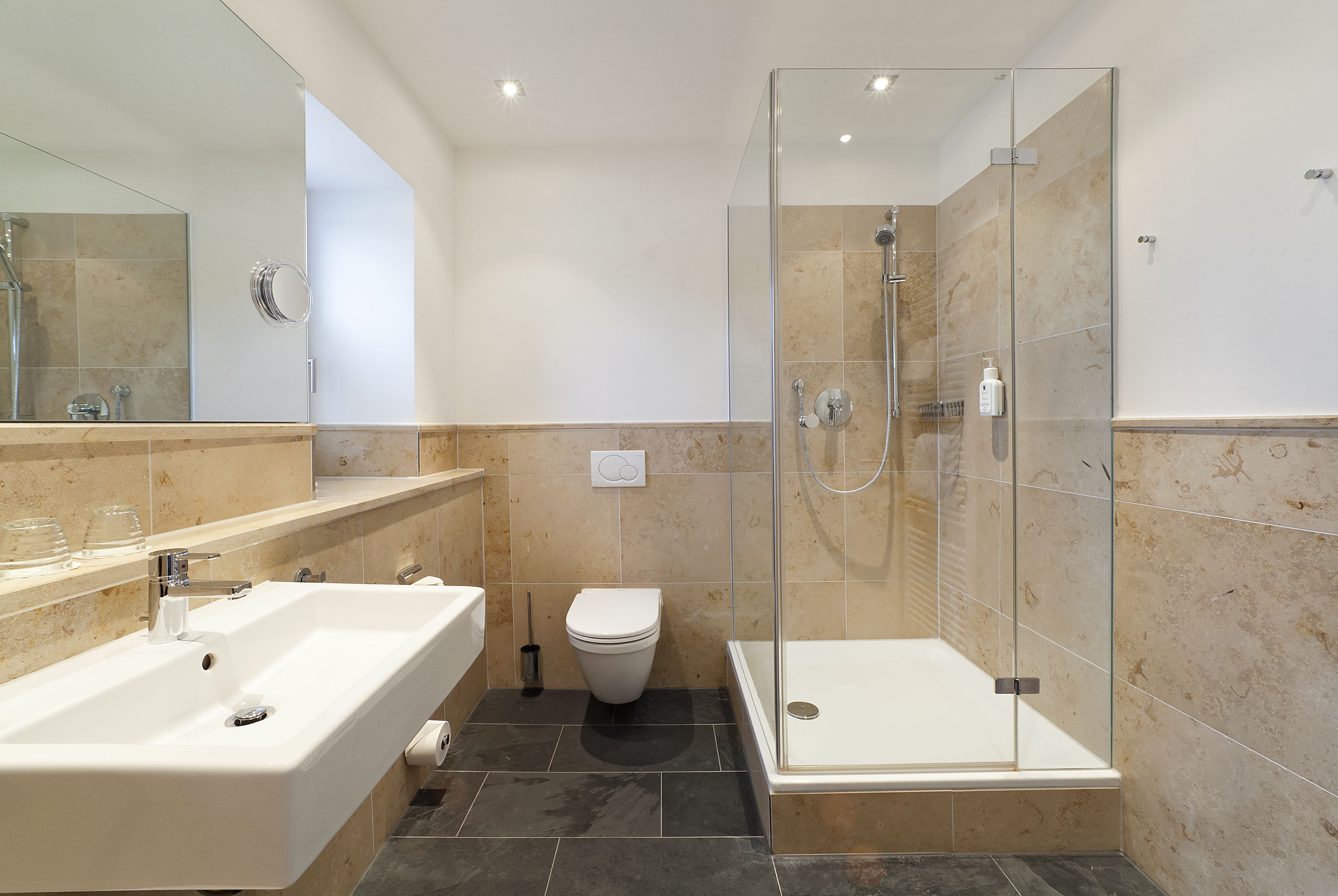 Un baño moderno con cabina de ducha de vidrio, lavamanos independiente y retrete.