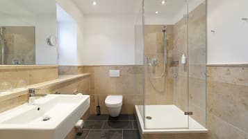 Un bagno moderno con cabina doccia in vetro, lavabo sospeso e water.