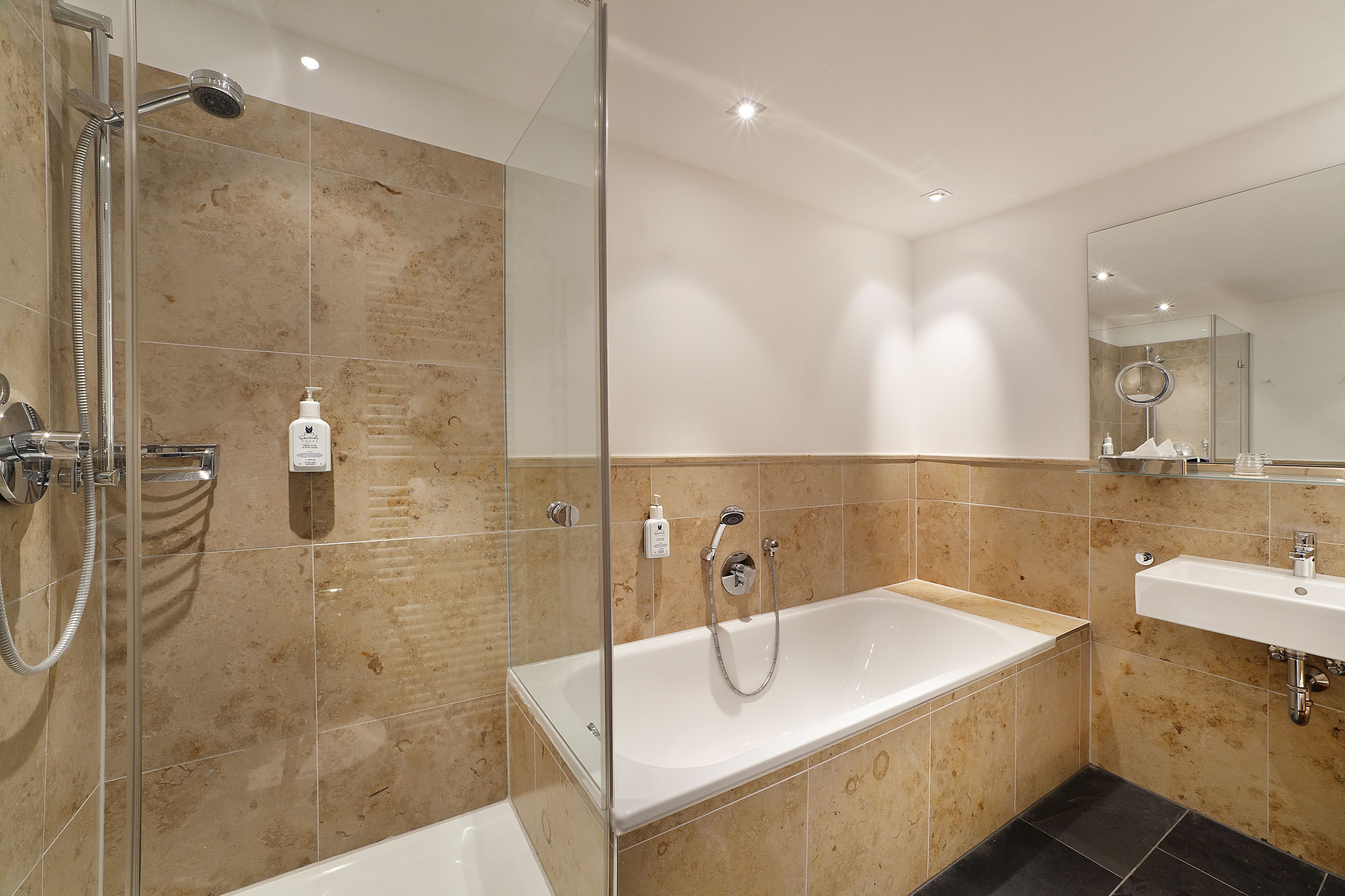 A modern bathroom with a glass-enclosed shower, a standalone bathtub, and a vanity with a sink.
