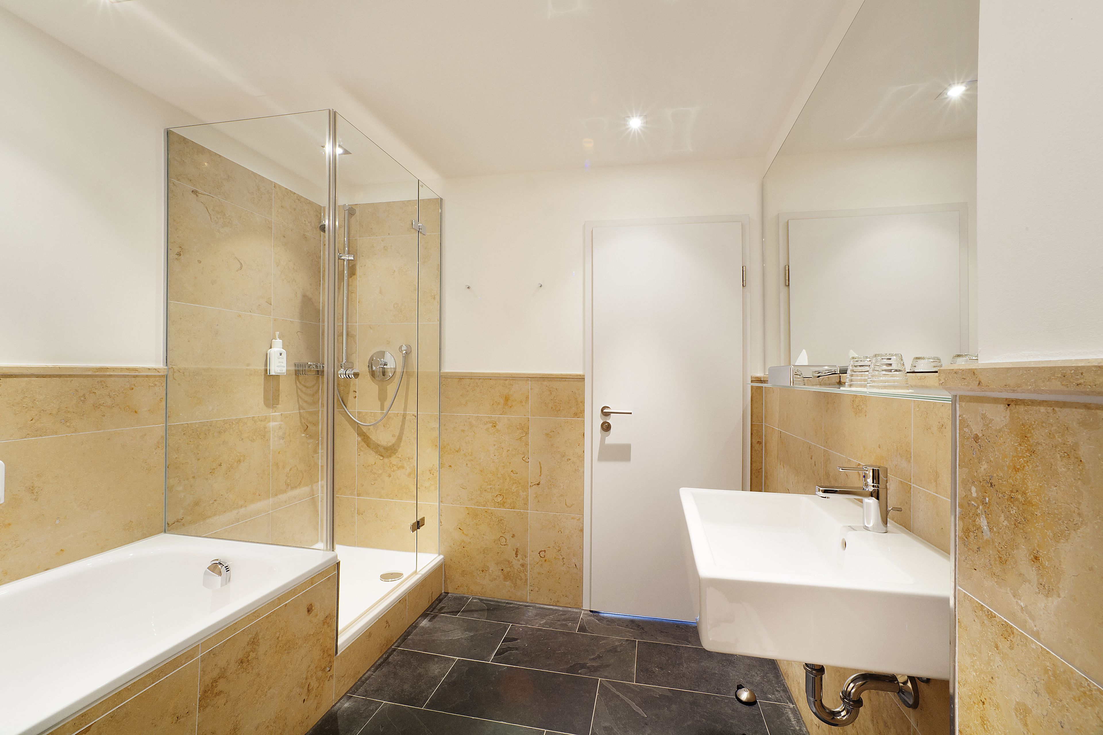 Une salle de bain moderne avec une douche à parois de verre, une baignoire sur pieds et un lavabo sur colonne.