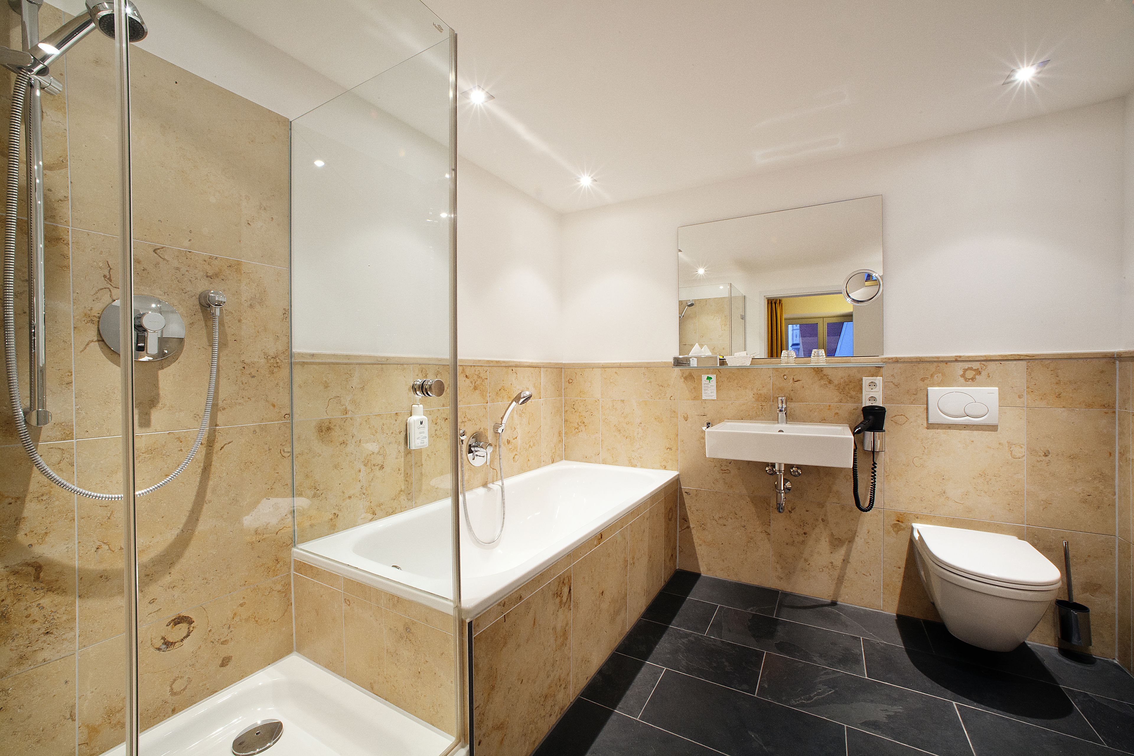 Un bagno moderno con doccia a parete in vetro, una vasca da bagno freestanding, un lavandino e un water.