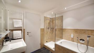 A modern bathroom with a glass-enclosed shower, a separate bathtub, and a vanity with a sink and towel rack.