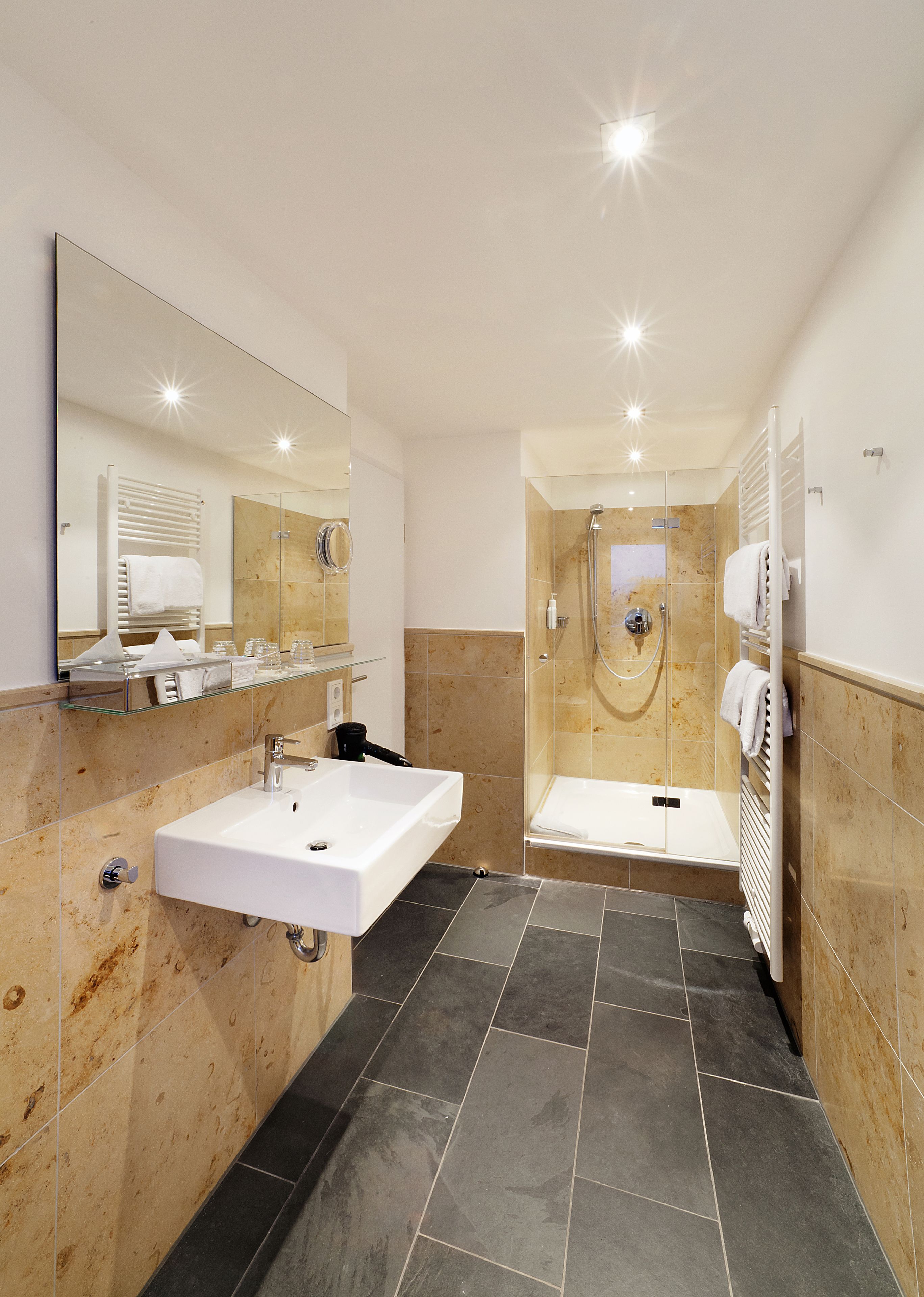 A modern bathroom with a white sink, a glass-enclosed shower, and a bathtub.