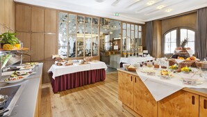 Ein reichhaltiges Buffet mit verschiedenen Speisen und eine Sitzgelegenheit mit Tisch und Stühlen.