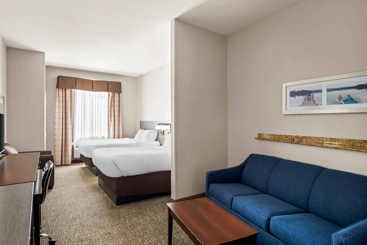 Ein Hotelzimmer mit einem Bett, einem blauen Sofa, einem Schreibtisch und einem gerahmten Bild an der Wand.